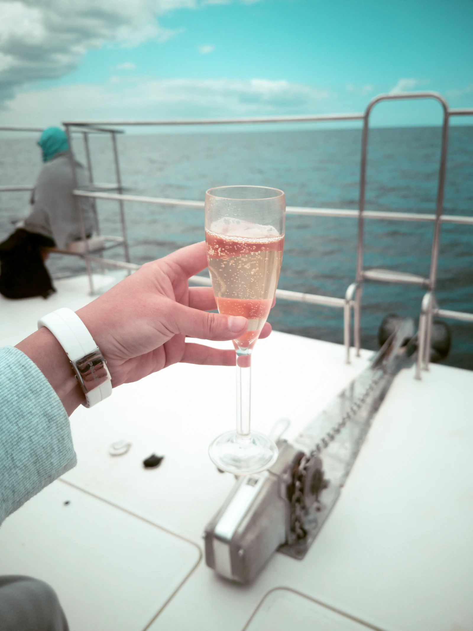 A glass of Champagne raised on a yacht